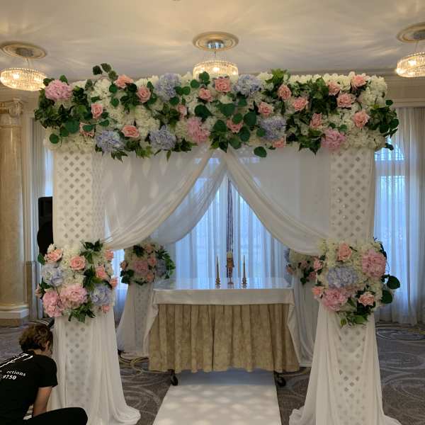 Wedding altar with pink and white floral arrangements and draped fabric