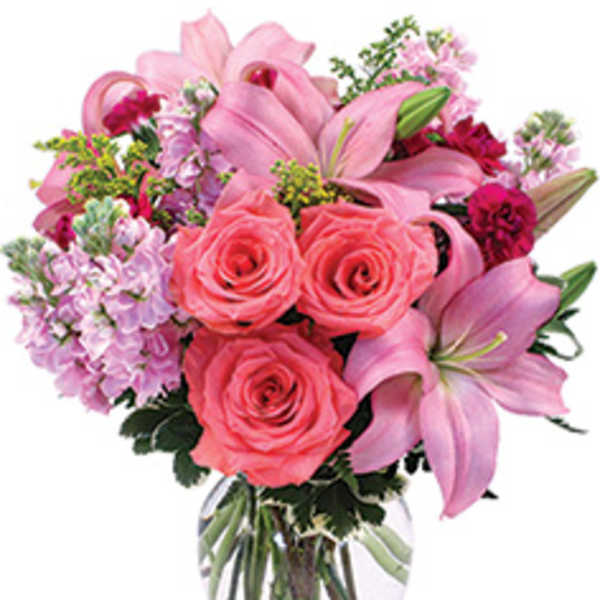 Pink roses and lilies arranged in a clear glass vase