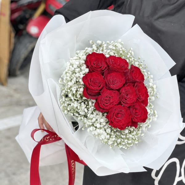 Bouquet of red roses with white baby's breath wrapped in white paper