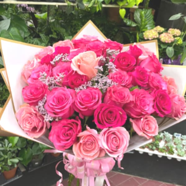 Large bouquet of pink and peach roses wrapped in white paper
