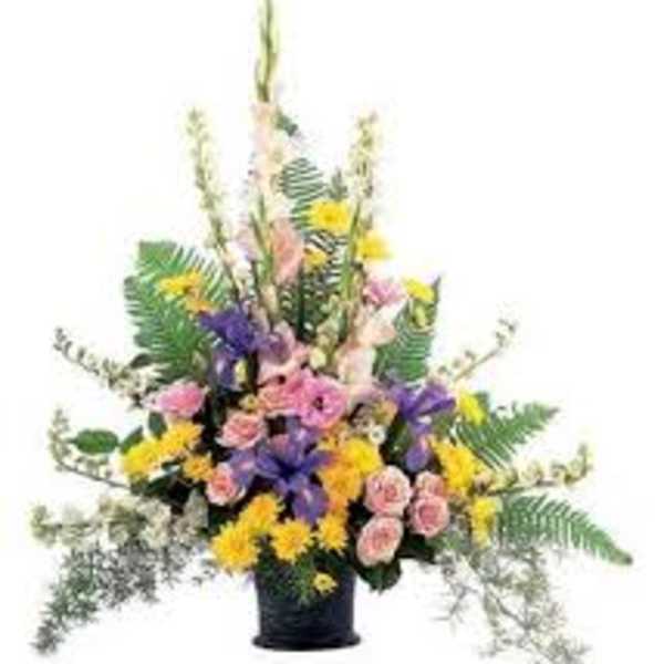 Tall mixed flower arrangement in a black vase with pink, yellow, and purple blooms