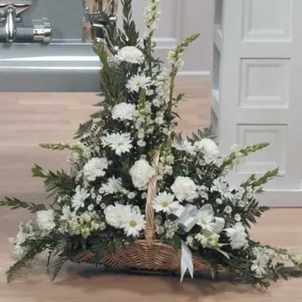 White floral basket arrangement with tall spikes and a white ribbon