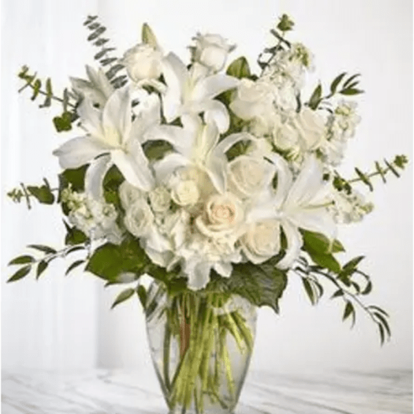 White lilies and roses arranged in a clear glass vase