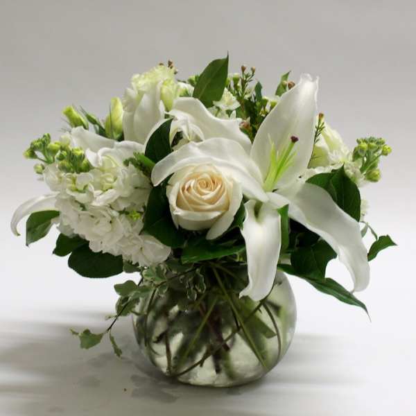White lilies and a cream rose in a glass vase