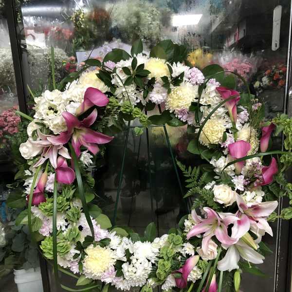 Large floral wreath with pink lilies and white blooms on a stand