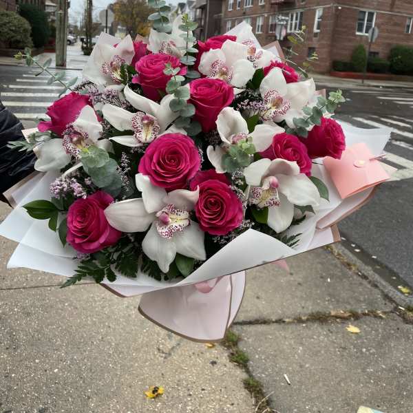 Bouquet of hot pink roses and white orchids wrapped in pale paper
