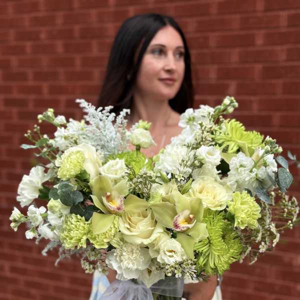 Large bouquet of pale green and white flowers in a glass vase