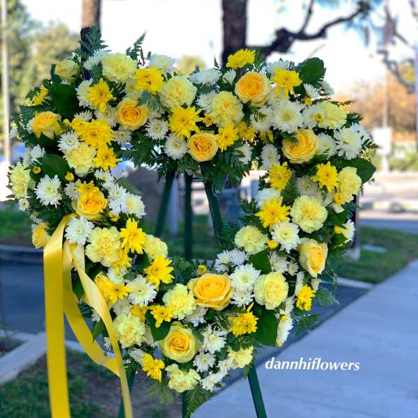 Heart-shaped yellow and white floral wreath on an easel with a ribbon