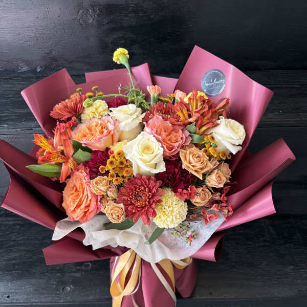 Mixed bouquet of roses, chrysanthemums, and alstroemeria wrapped in pink paper