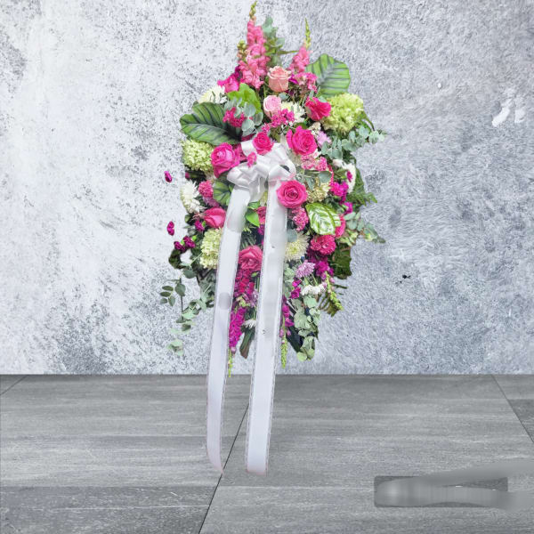 Standing floral spray with pink roses and a white ribbon bow