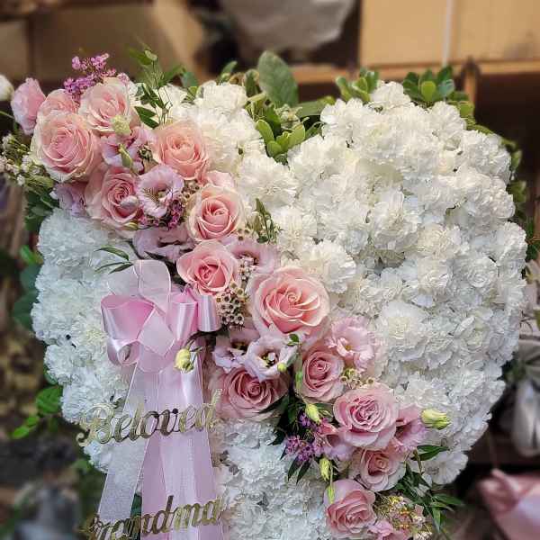 Heart-shaped floral arrangement with pink roses and white carnations