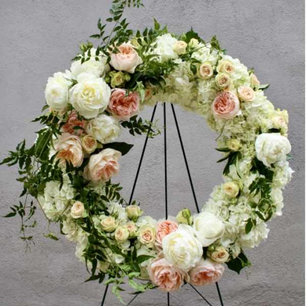 Floral wreath of white and peach roses on a black stand