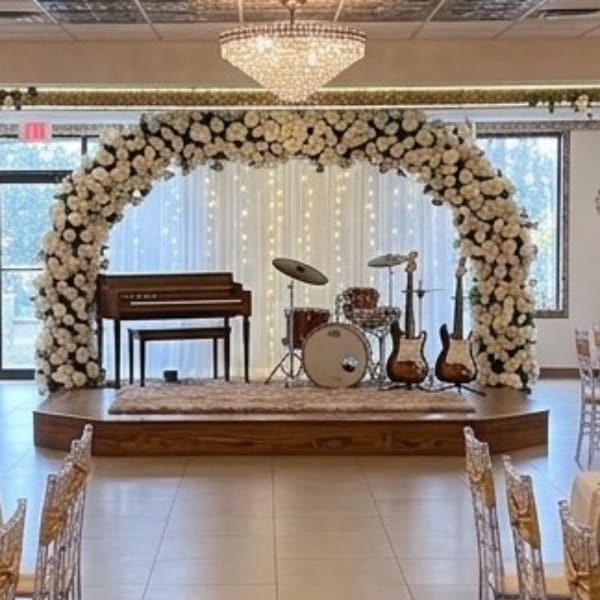 White floral arch framing a small stage with instruments