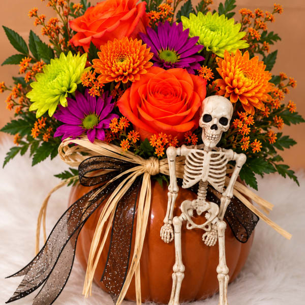 Halloween bouquet in a pumpkin vase with a small skeleton decoration