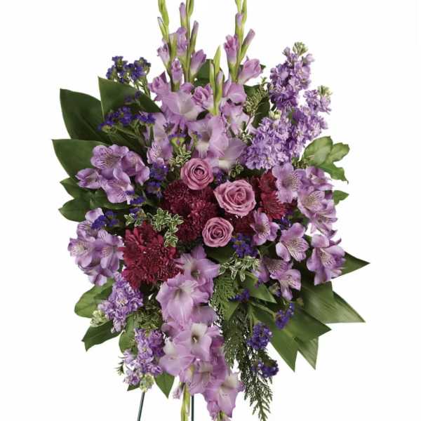 Standing spray of purple flowers with pink roses on a wire easel