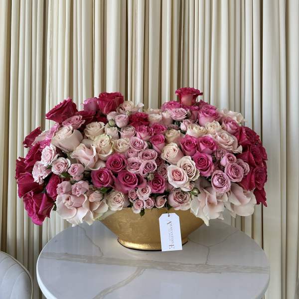 Large pink and white rose arrangement in a gold vase