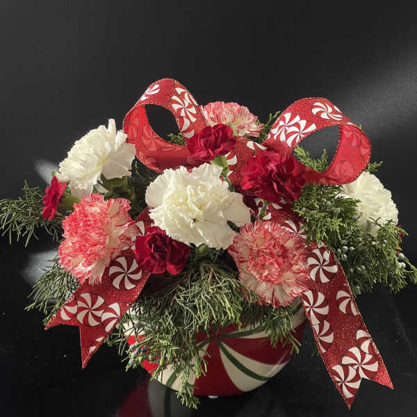 Holiday floral arrangement with red and white carnations in a candy cane vase