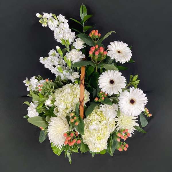 White floral wreath with gerbera daisies and hydrangeas on a dark background