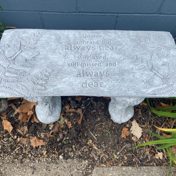 Stone memorial bench with an engraved sympathy message and butterfly reliefs