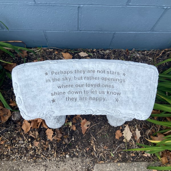Stone memorial bench with an engraved sympathy quote outdoors