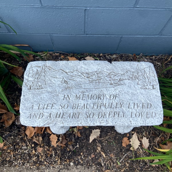 Memorial stone with engraved text in a garden bed