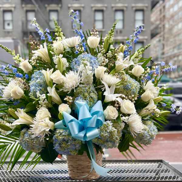Large basket arrangement of white and blue flowers with a blue ribbon