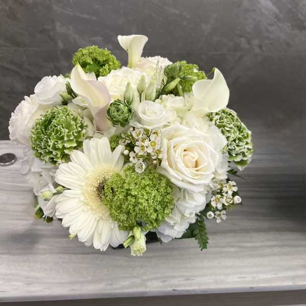 White and green floral arrangement with roses, calla lilies, and a gerbera daisy