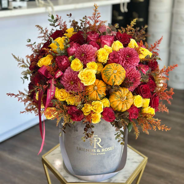 Bouquet of red and yellow roses with pink dahlias in a gray hatbox