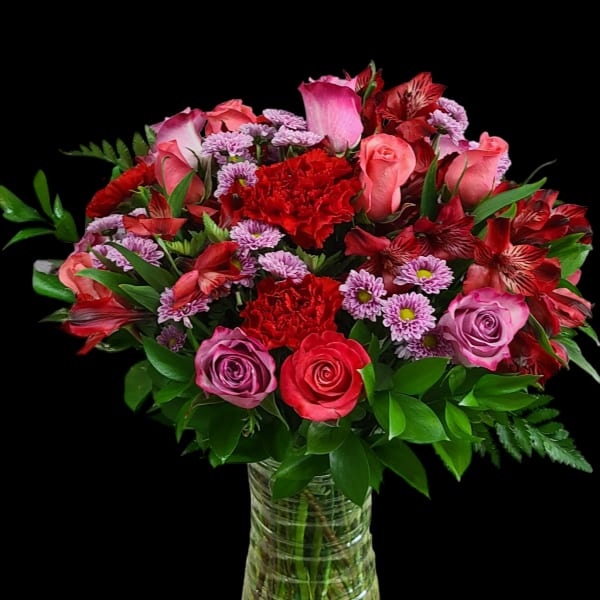 Bouquet of pink and red roses with carnations in a glass vase