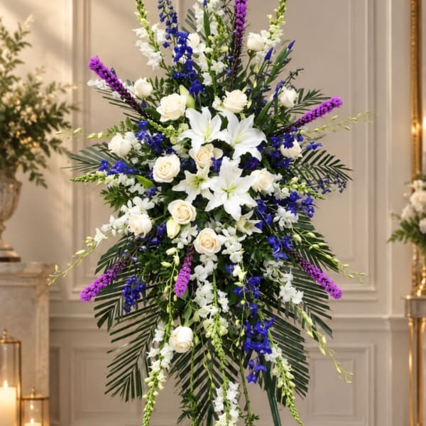 Tall standing floral spray with white lilies, roses, and blue-purple flowers