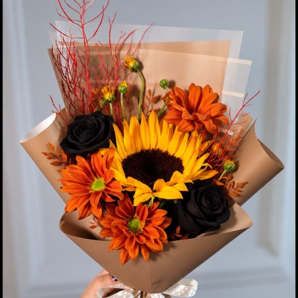 Bouquet with a sunflower, orange daisies, and black roses in brown wrap