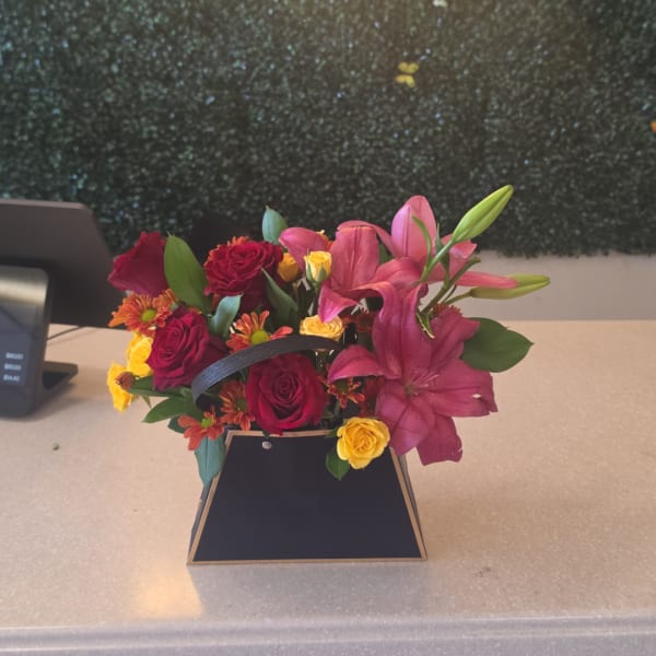 Pink lilies and red roses in a black handled box