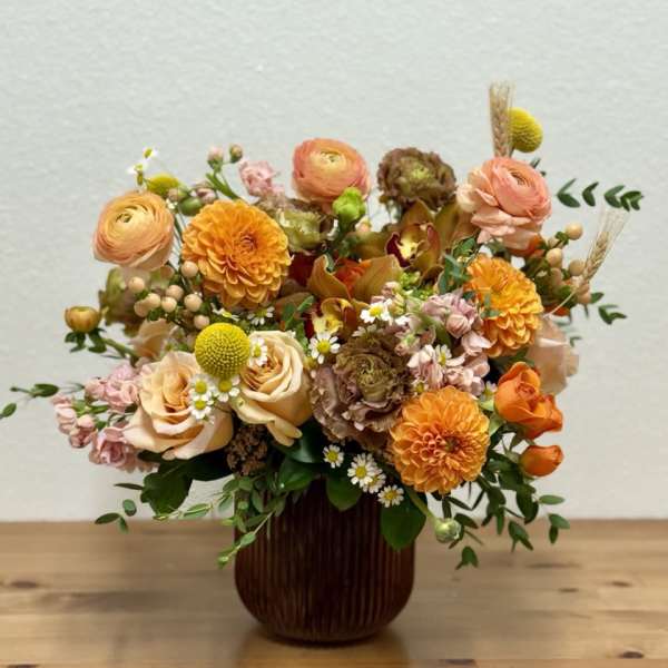 Mixed orange and peach flowers arranged in a dark vase
