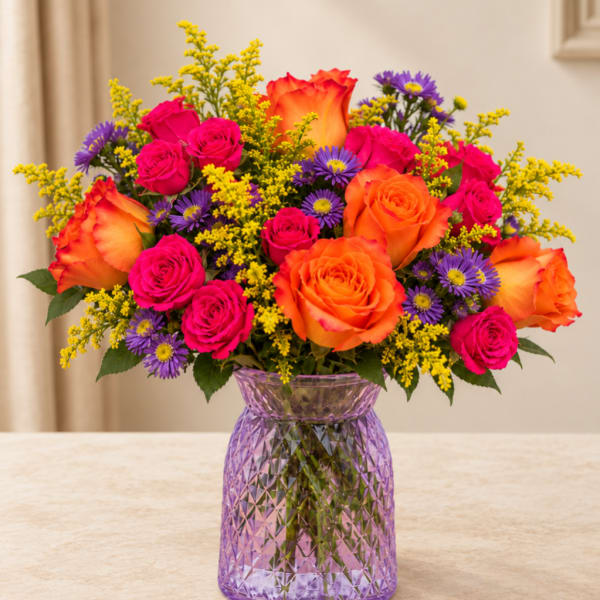 Bouquet of orange and pink roses with purple daisies in a purple vase