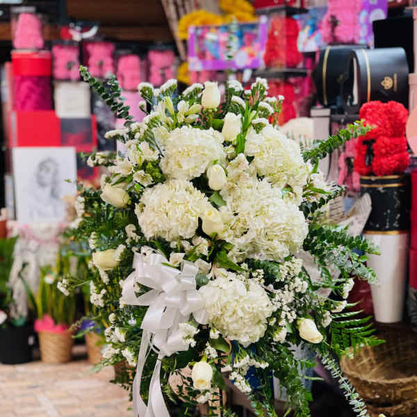 White floral standing spray with a ribbon bow