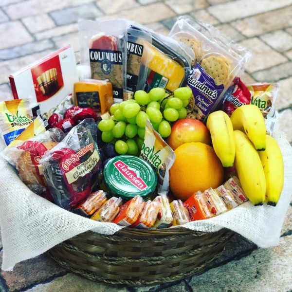 Gift basket with fruit, crackers, cheese, and packaged snacks