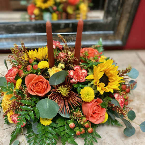 Low floral centerpiece with sunflowers, roses, and two candles