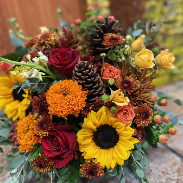 Mixed bouquet with red roses, sunflowers, and orange blooms in autumn colors