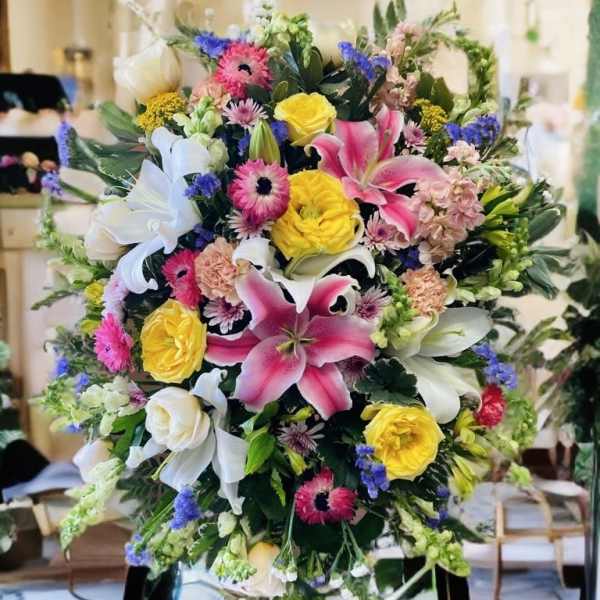 Large standing floral spray with pink lilies, yellow roses, and white blooms