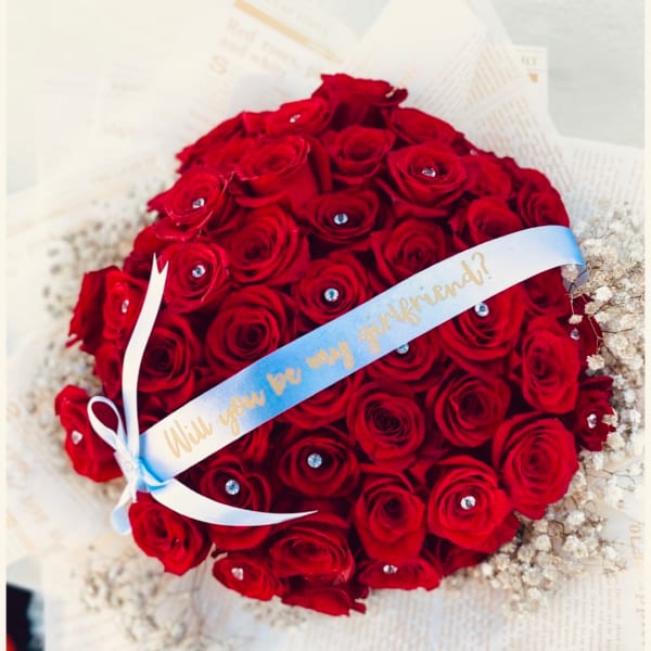 Round bouquet of red roses with a ribbon across the front