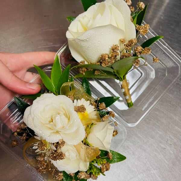 Two small white rose boutonnieres in clear plastic cases