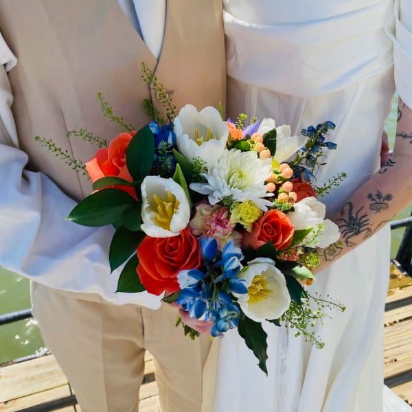 Bride and groom holding a colorful bouquet with roses and tulips