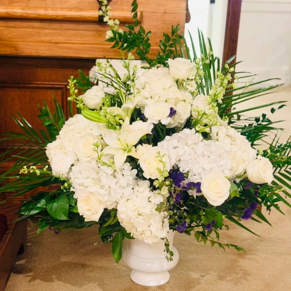 White floral arrangement in a white pedestal vase
