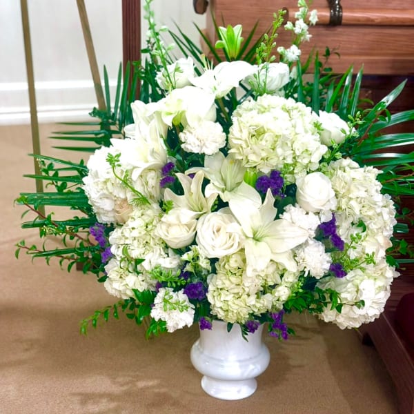 White floral arrangement in a white vase with purple accents