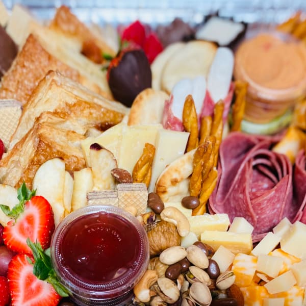 Charcuterie board with cheese, crackers, fruit, nuts, and jam