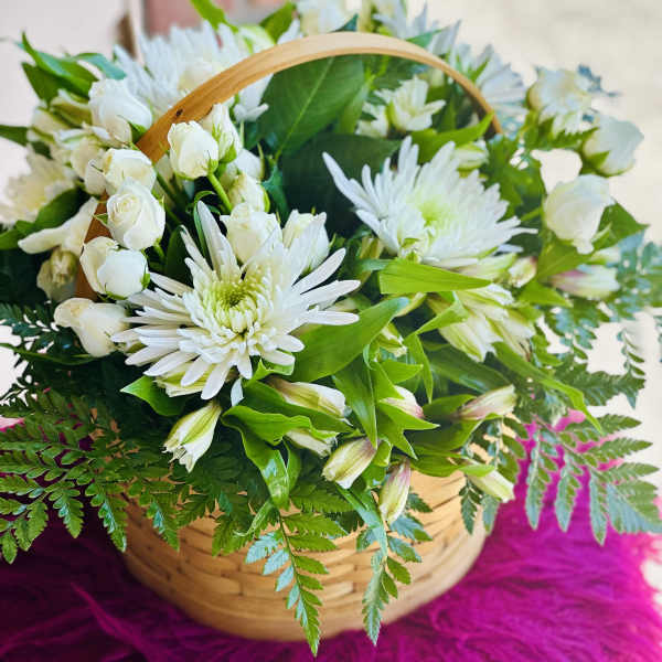 Basket of white flowers with green foliage and a wooden handle