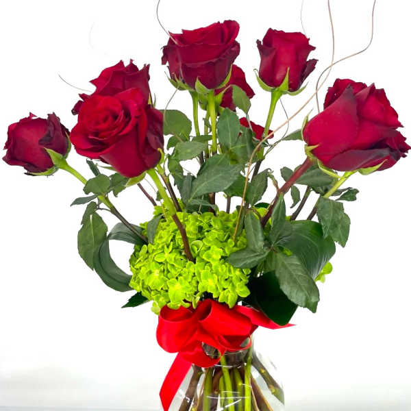 Red roses arranged in a clear glass vase with a red ribbon