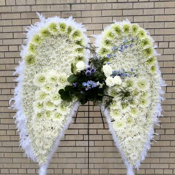 Large white floral funeral wreath shaped like angel wings