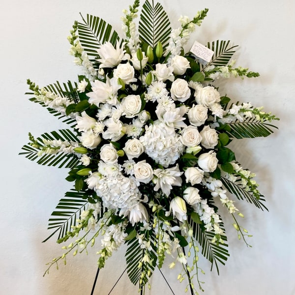 Large white floral standing spray on an easel with roses and lilies