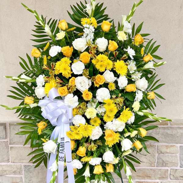 Large yellow and white funeral wreath with ribbon on an easel